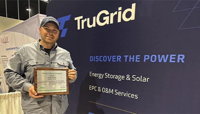 Justin Whittenburg holding a National Safety Council Perfect Record Award at a TruGrid event booth